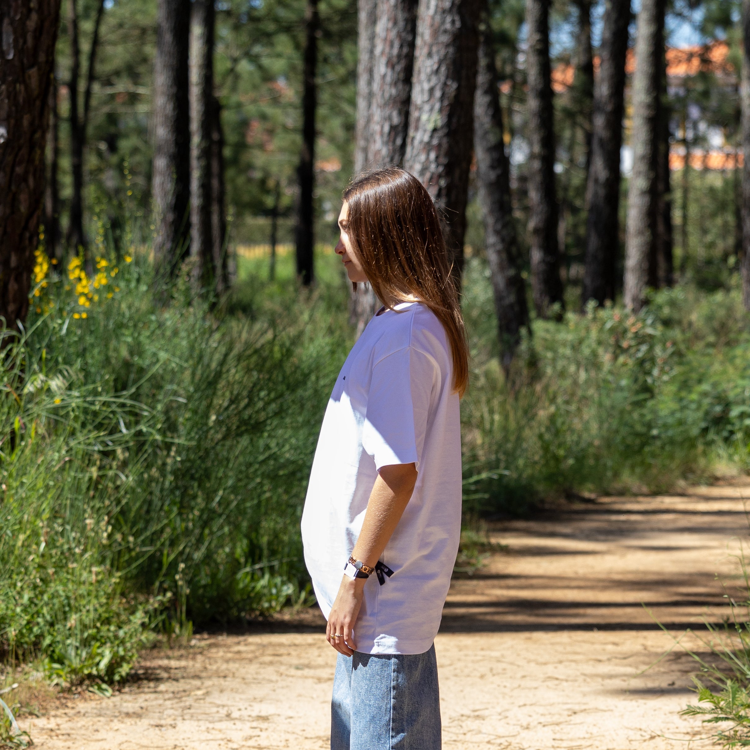 Sideprofil af kvindelig model i hvid heavy T-shirt – 100% økologisk og produceret i Europa med enkelt udtryk