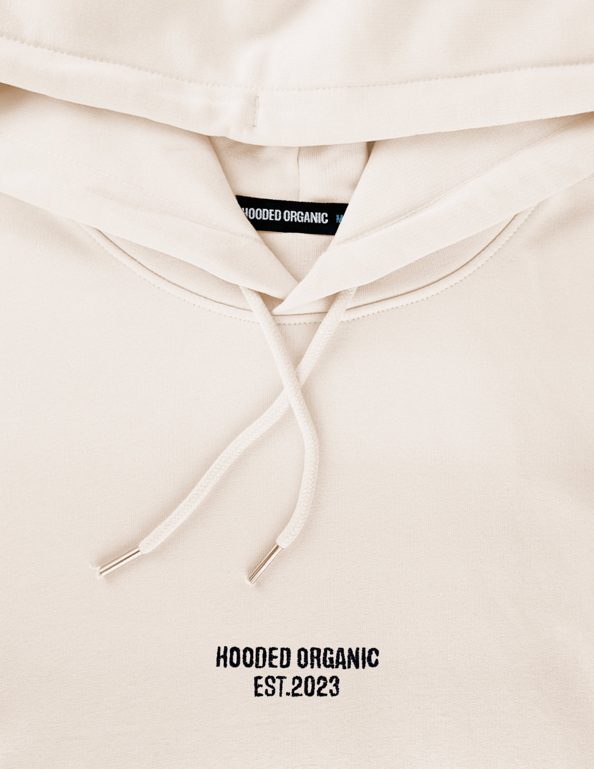 Detalje af beige hoodie med broderet Hooded Organic-logo – 100% økologisk bomuld
