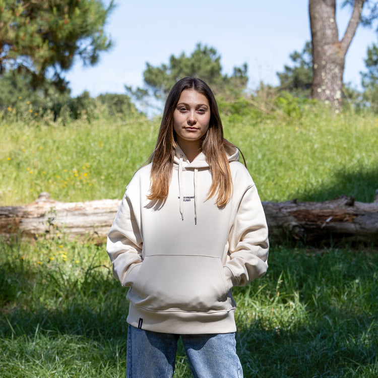 Beige hoodie forfra med hætten nede – Hooded Organic-logo og 100% økologisk bomuld
