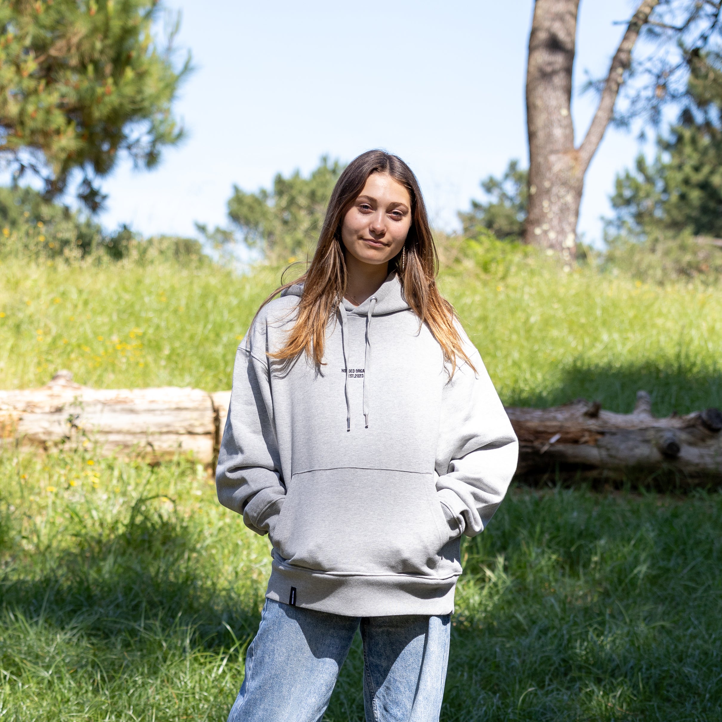 Kvindelig model i grå hoodie med hætten nede – 100% økologisk tekstil og tidløst dansk design