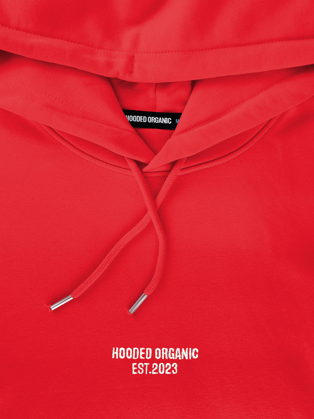 Close-up af Hooded Organic-logo på rød hoodie – produceret i 100% økologisk bomuld
