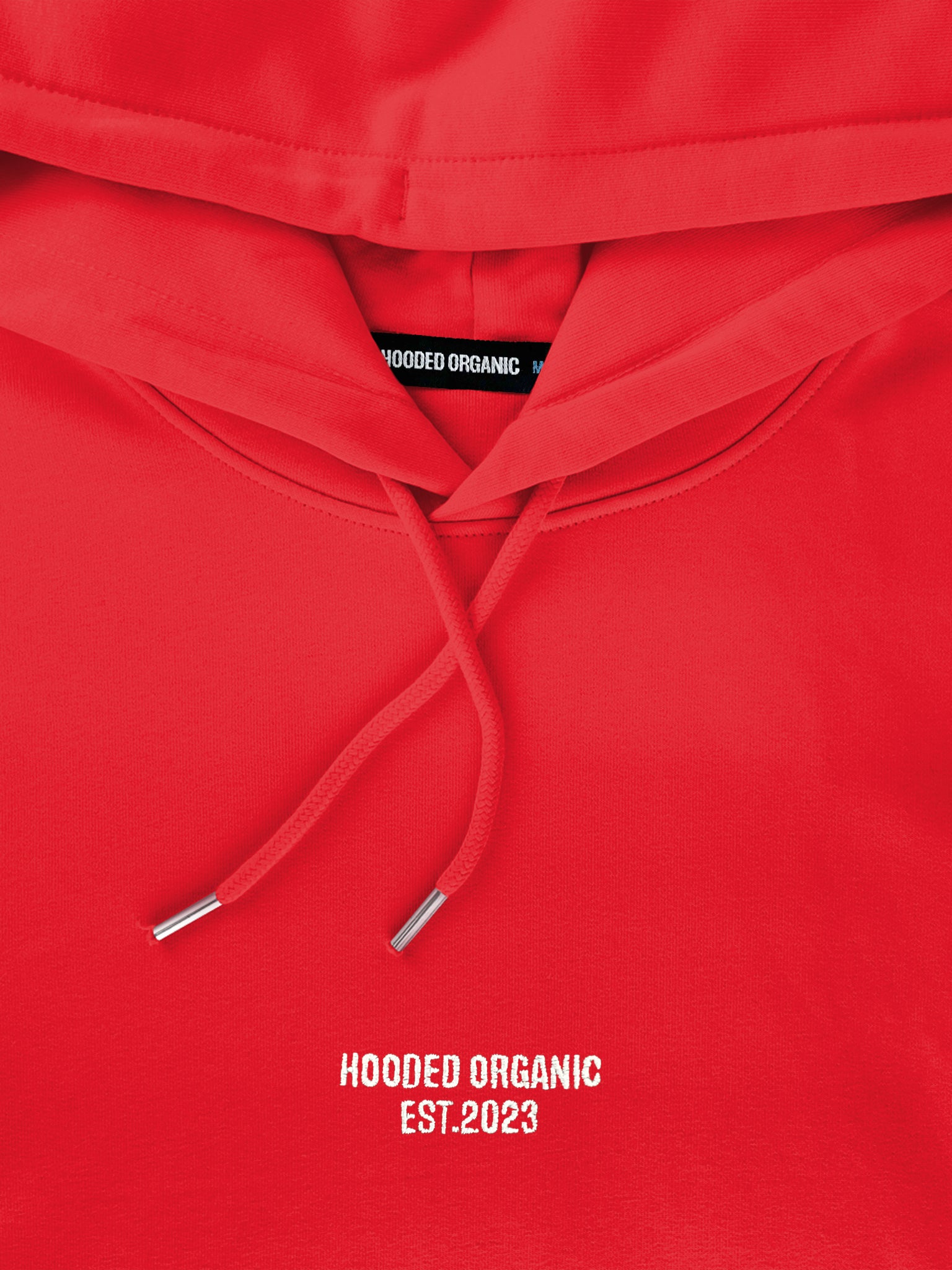 Close-up af Hooded Organic-logo på rød hoodie – produceret i 100% økologisk bomuld
