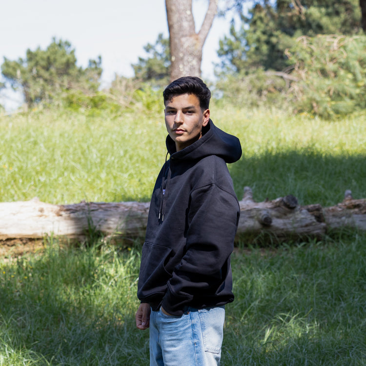 Sidelæns frontvisning af sort hoodie med hætten nede – fremstillet i 100% økologisk bomuld
