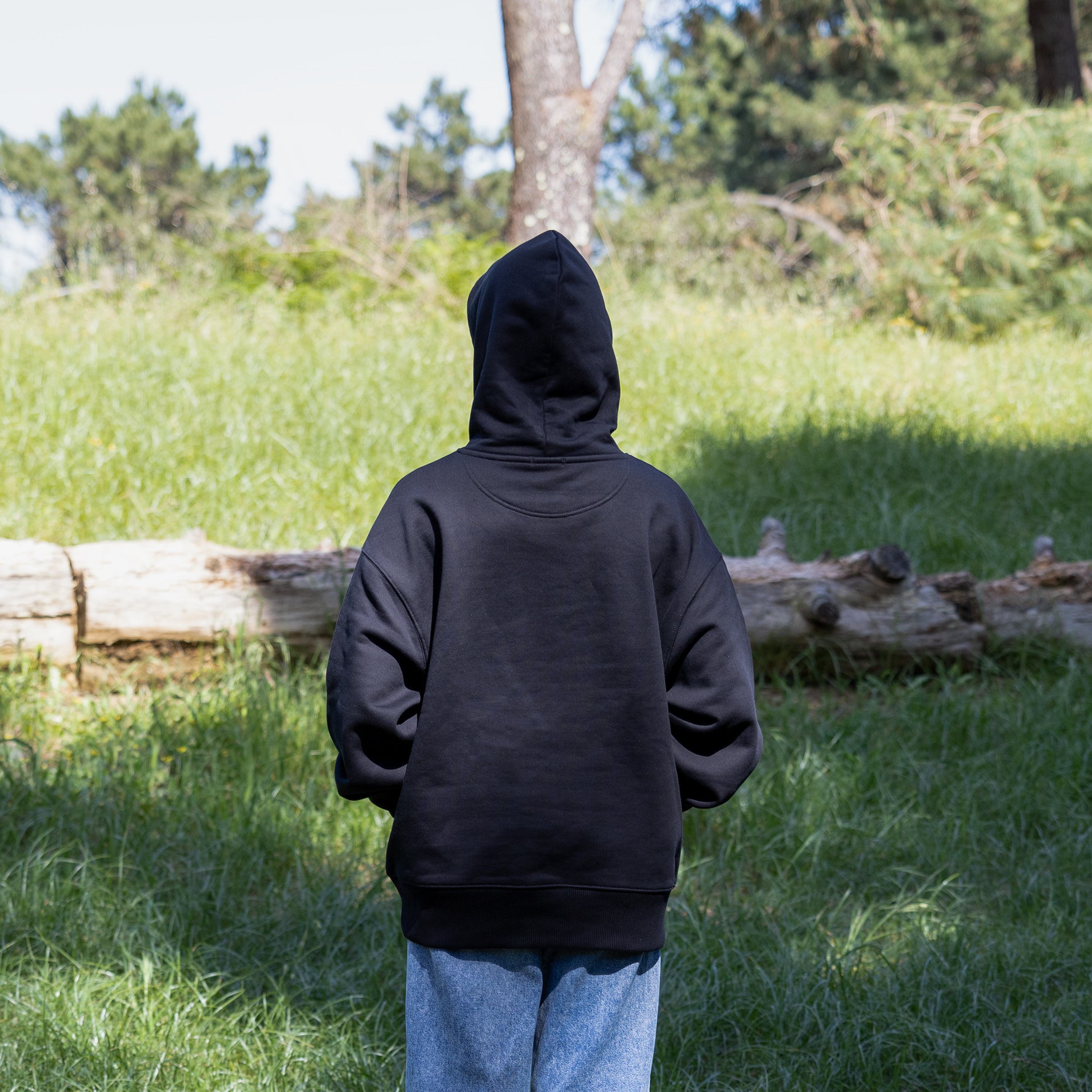 Sort hoodie med hætten oppe på kvindelig model – 100% økologisk bomuld og visuel styrke i dansk stil