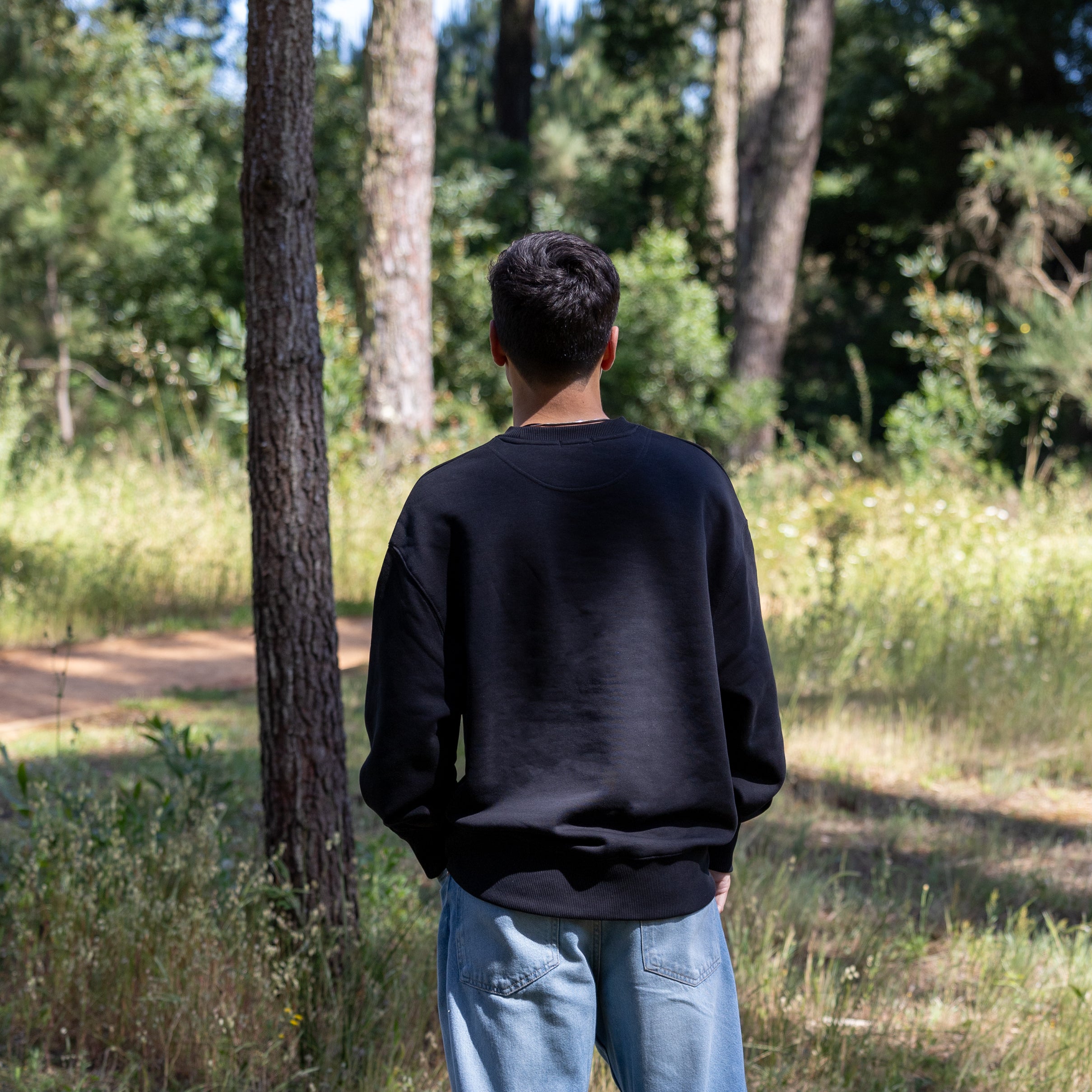 Sort sweatshirt på mandelig model set bagfra – 100% økologisk bomuld og ren silhuet
