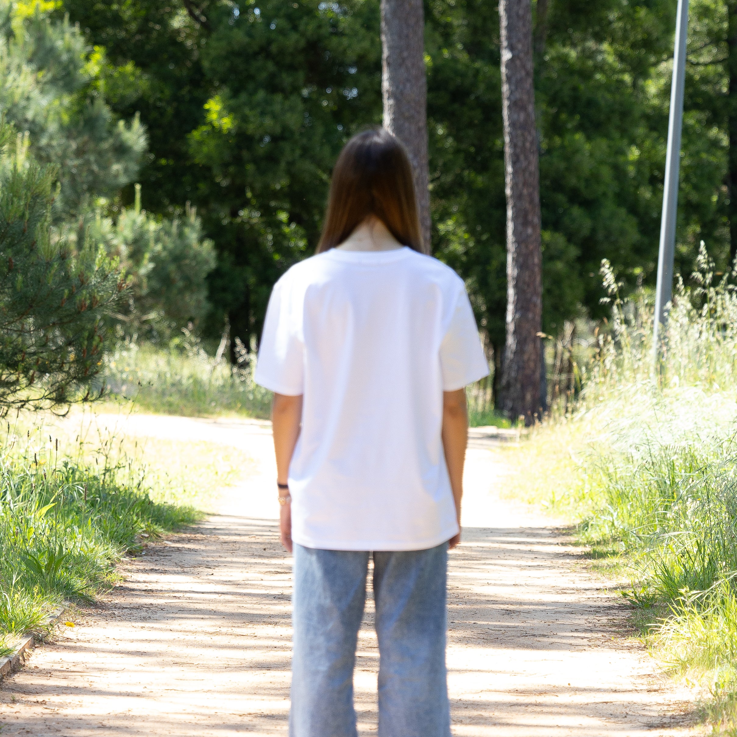Kvindelig model i hvid T-shirt set bagfra – dansk design i 100% økologisk bomuld
