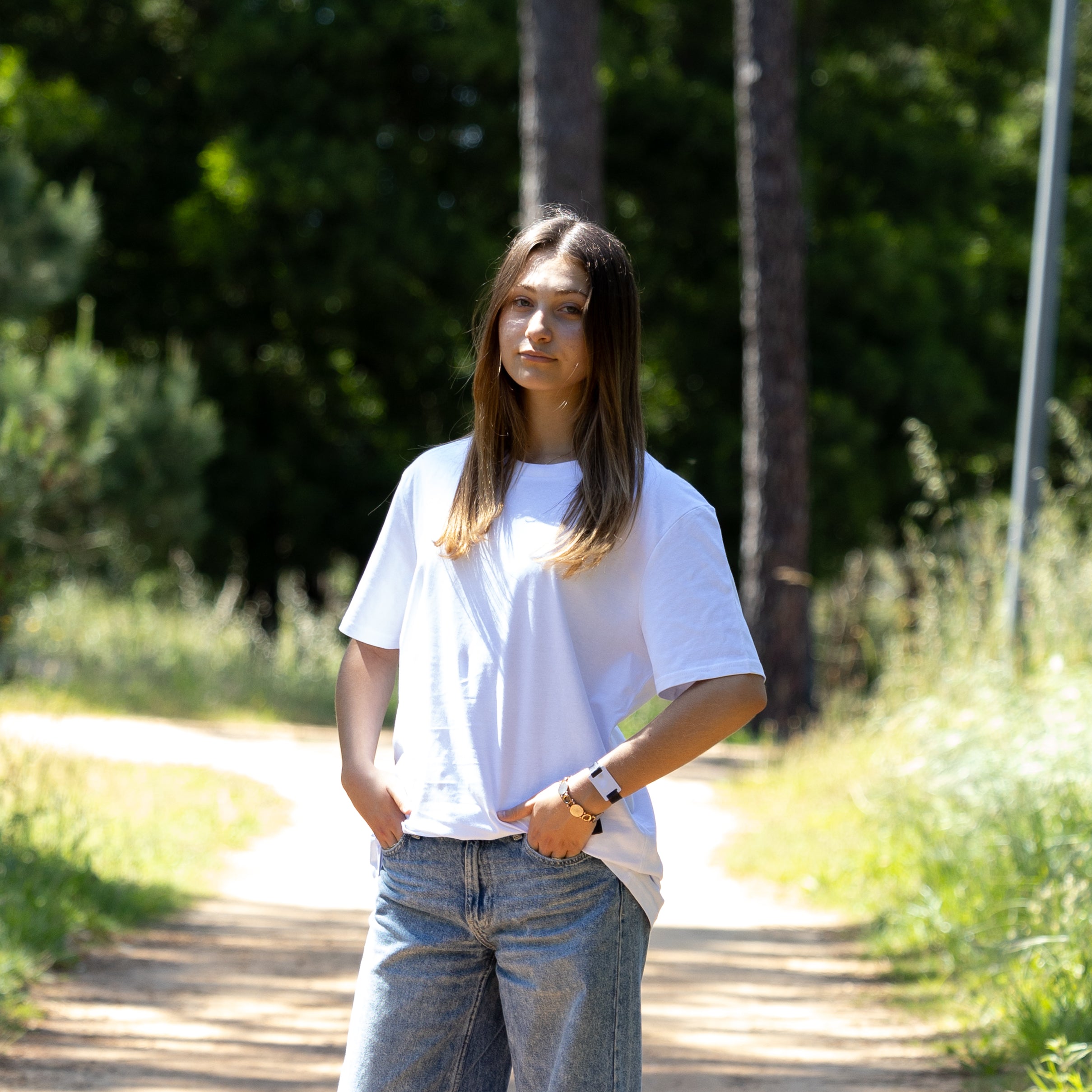 Hvid T-shirt vendt let sidelæns på kvindelig model – 100% økologisk og diskret cool
