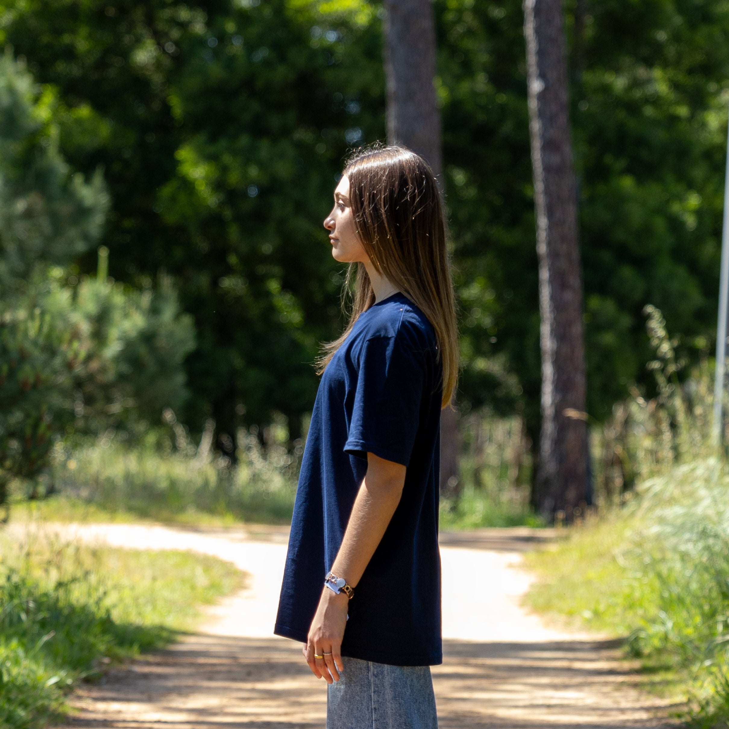 Sidevisning af navy T-shirt i naturmiljø – 100% økologisk bomuld og blød komfort