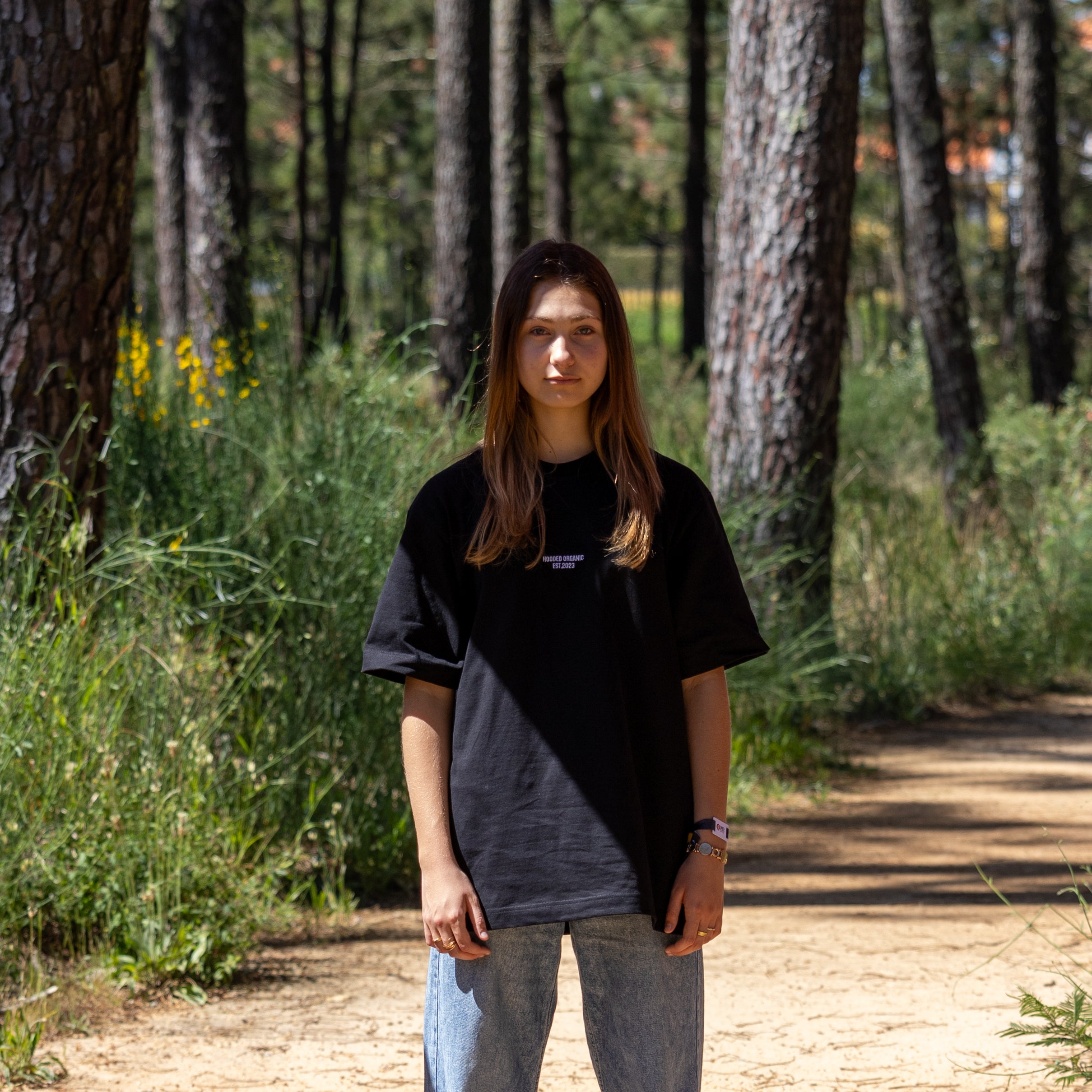 Kvindelig model i sort T-shirt med Hooded Organic-logo – forfra i naturen med dansk design og økologisk kvalitet